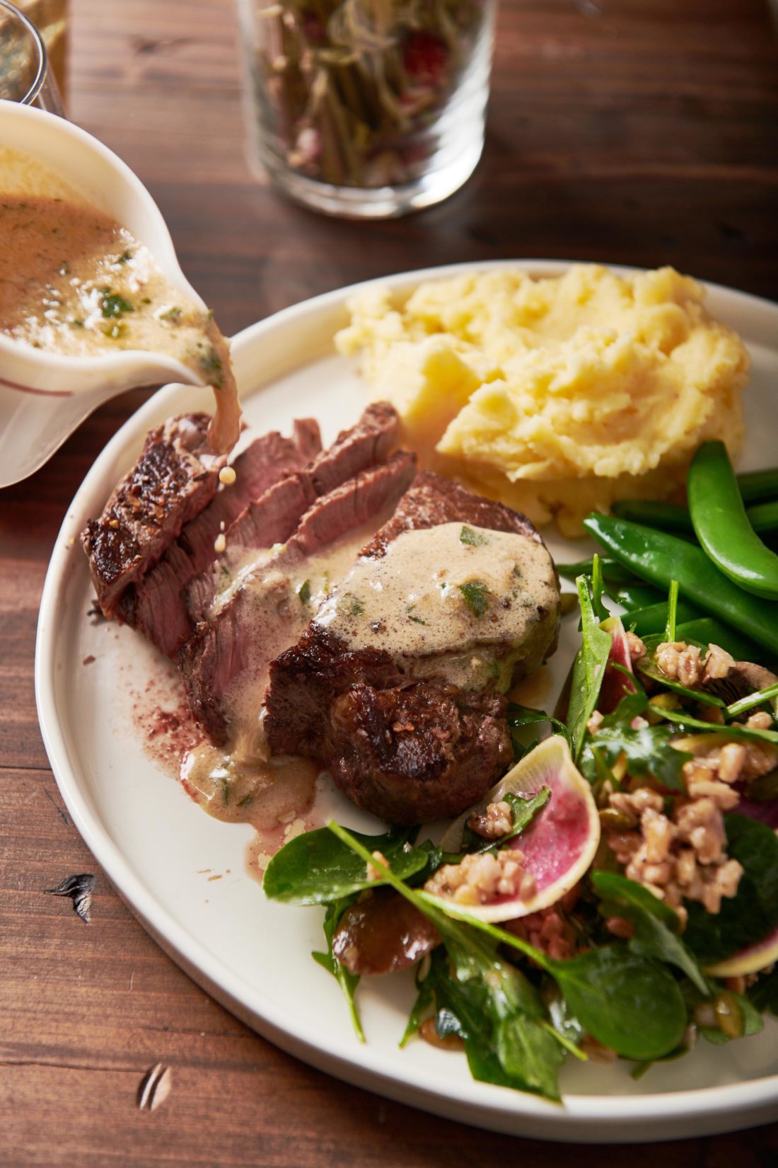 Creamy Parmesan Mustard Sauce pouring over a plate of sliced filet mignon.