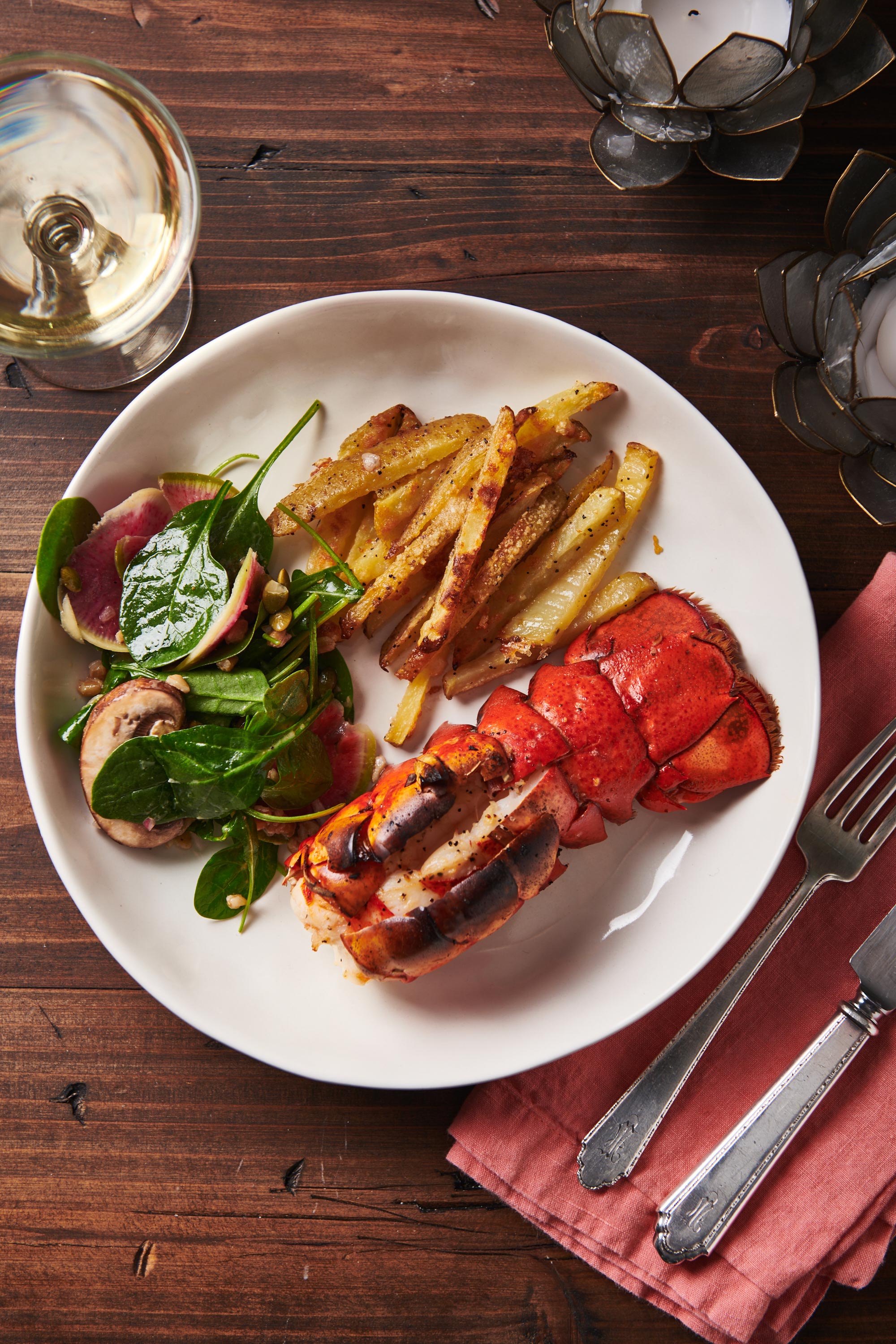 Broiled Lobster Tail with salad and french fries on a plate.