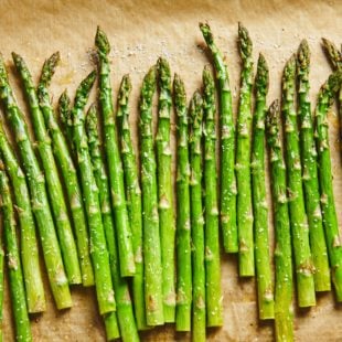 Parchment paper with a line of Roasted Asparagus.