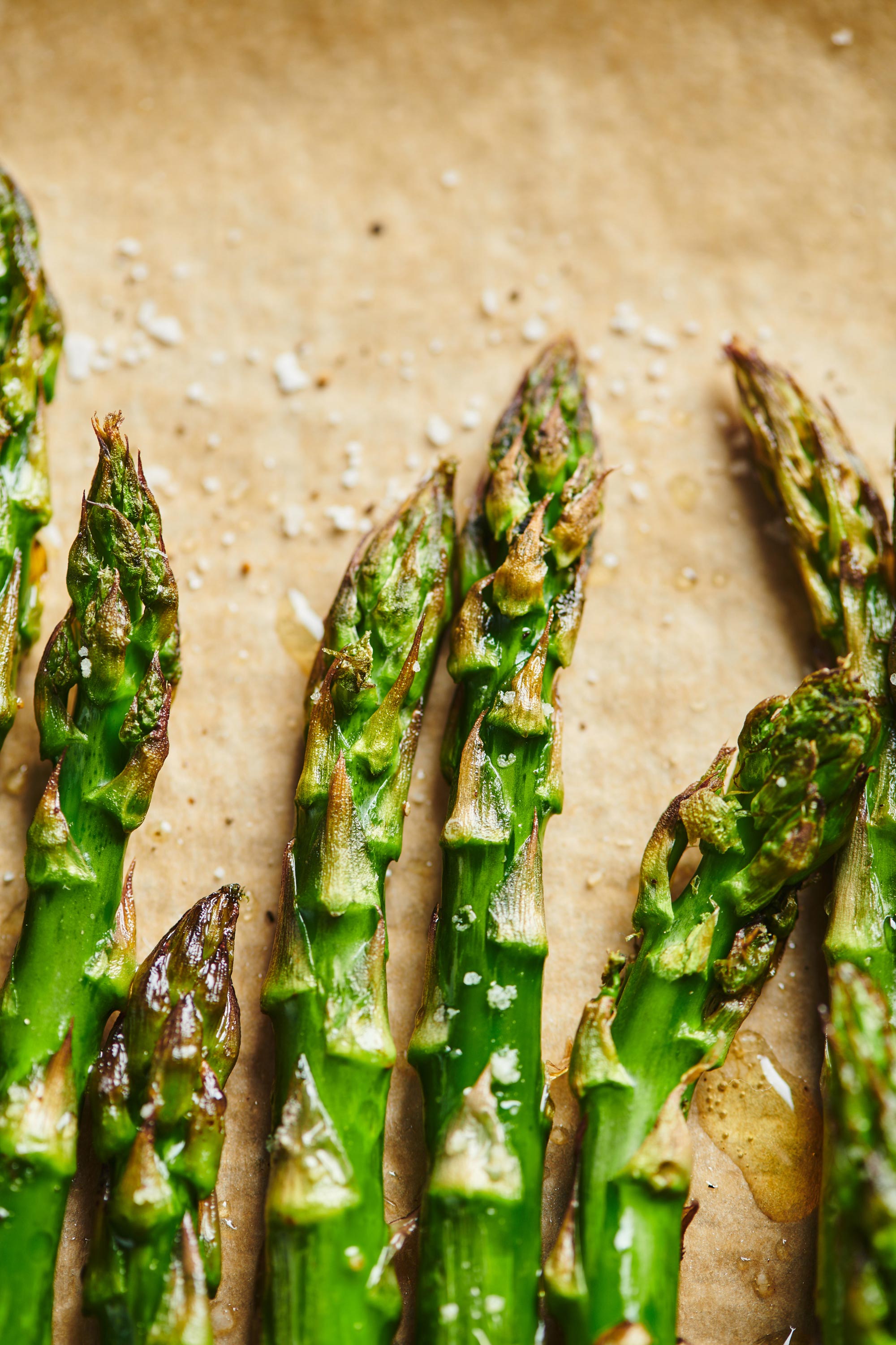 Roasted Asparagus with salt and pepper on parchment paper.