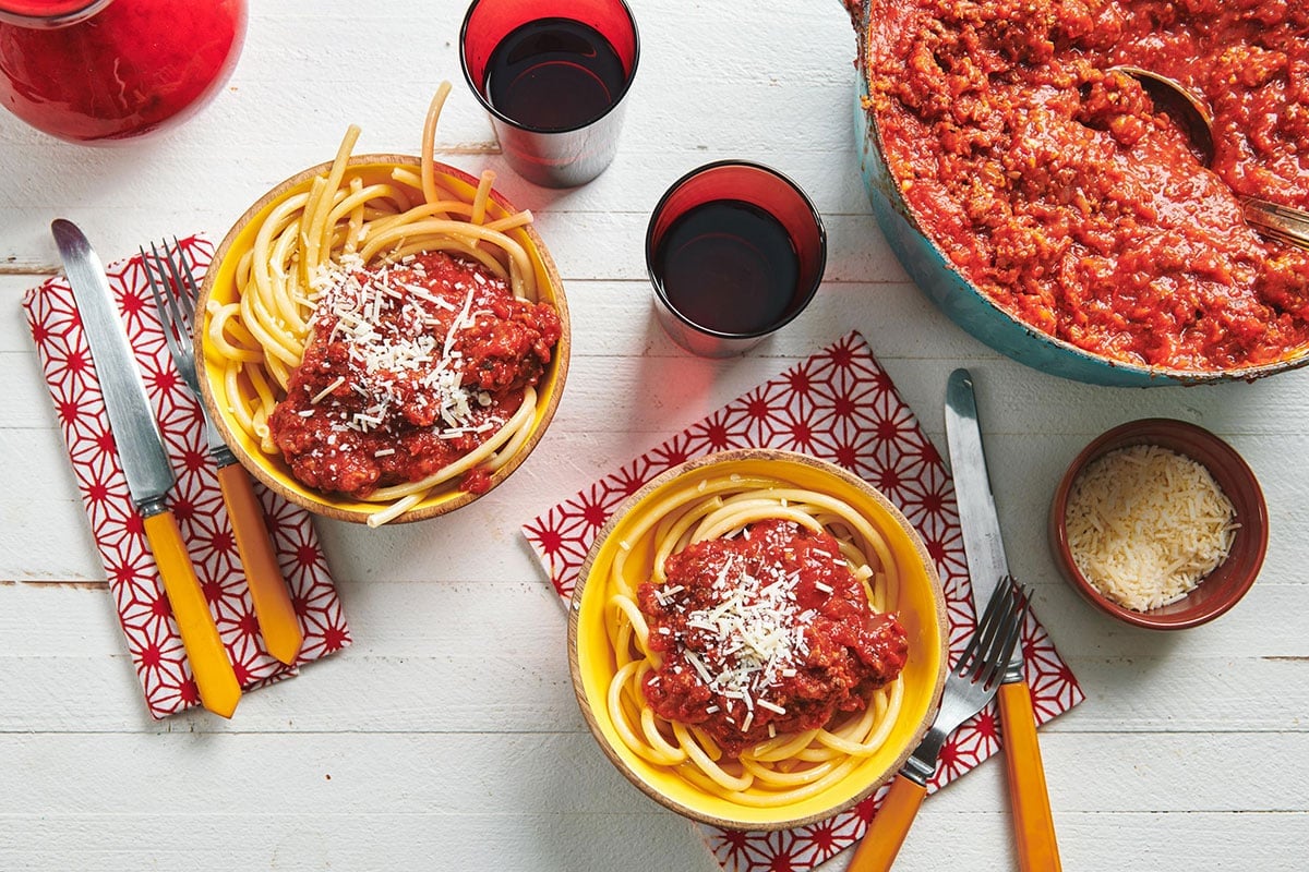 Table set with pan of meat sauce and bowls with spaghetti and sauce.