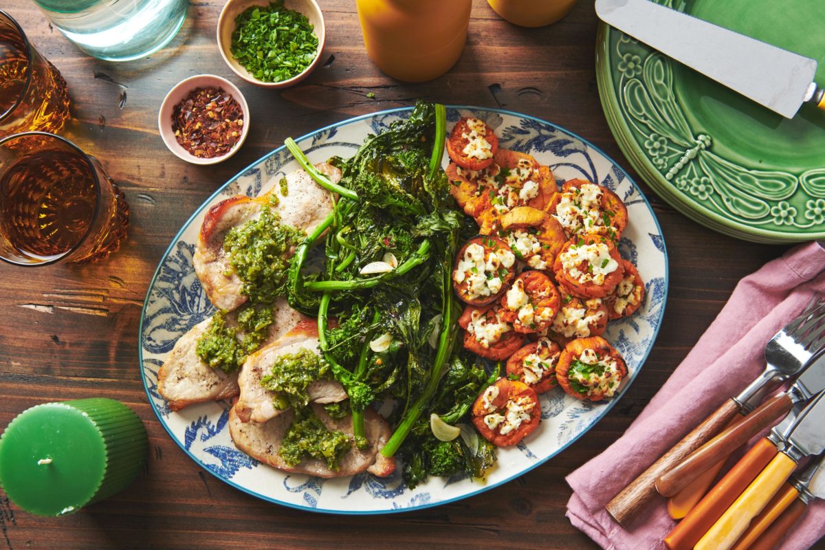 Blue and white platter of Pork Chops with Italian Salsa Verde, broccoli rabe, and sweet potatoes.