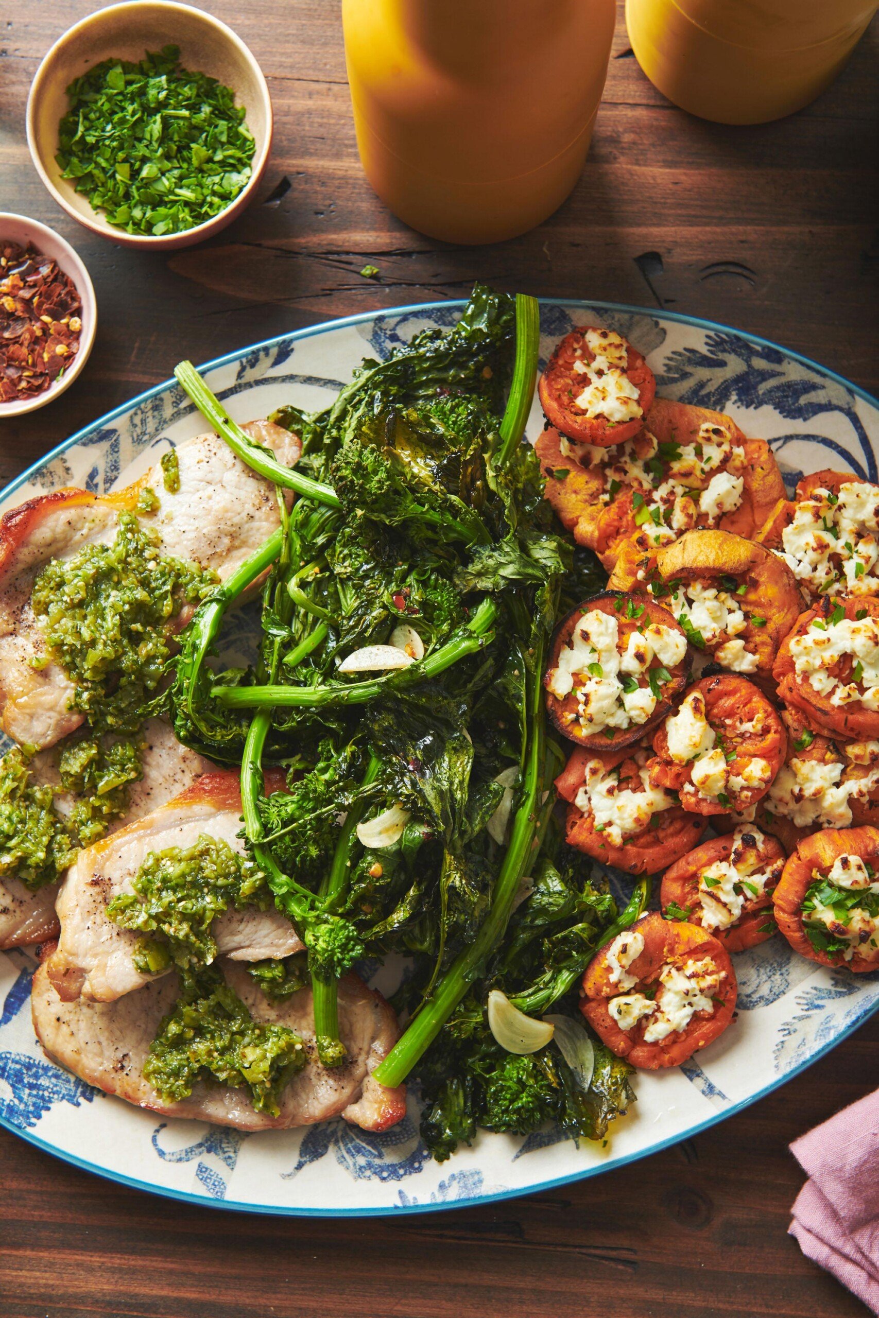 Pork Chops with Italian Persillade on a platter with broccoli rabe and sweet potatoes.