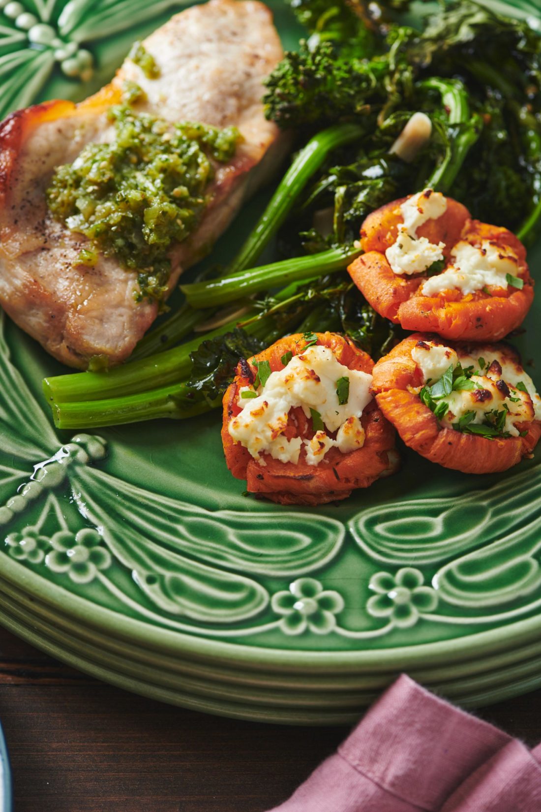 Pork Chops with Italian Salsa Verde, broccoli rabe, and sweet potatoes on a green plate.