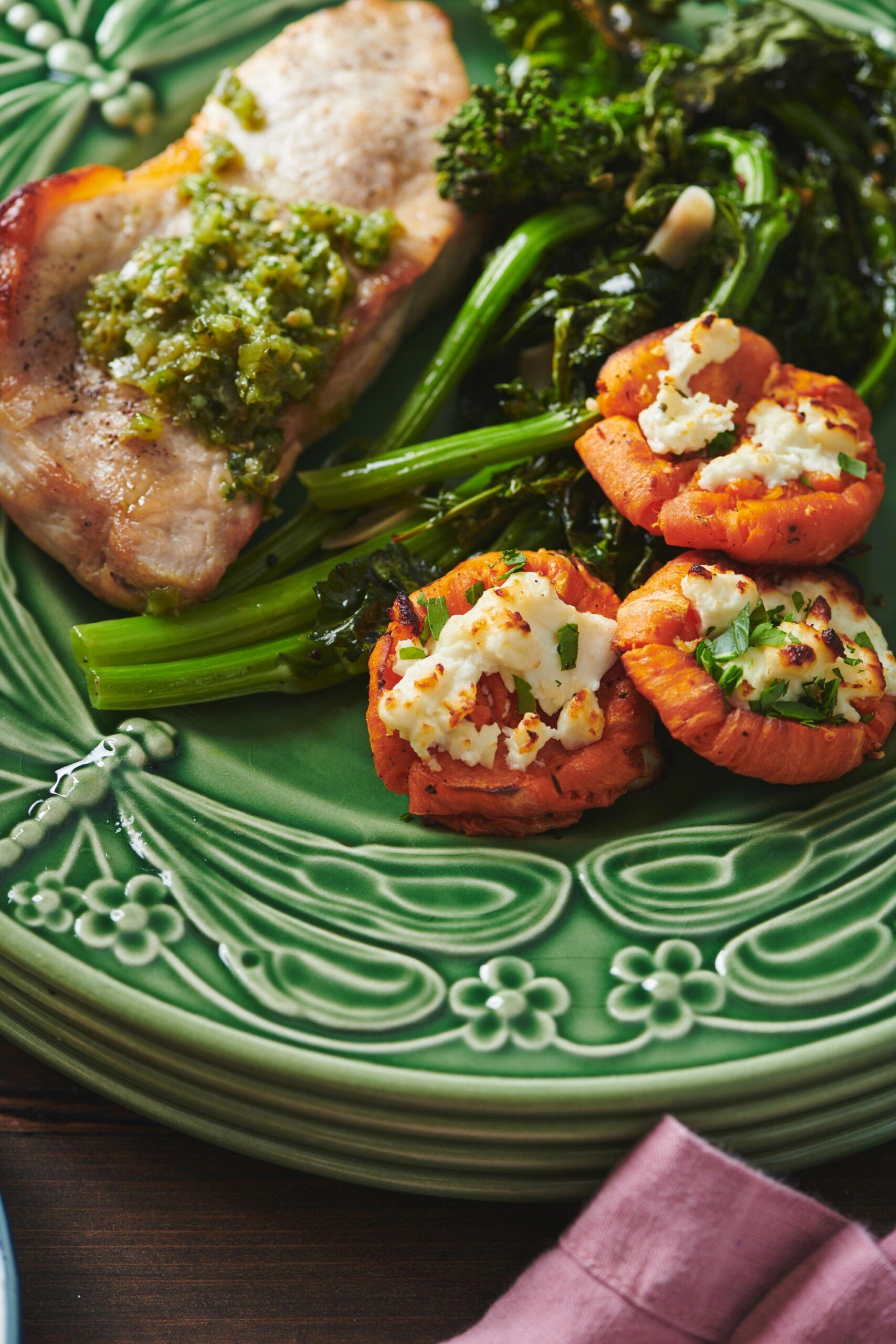 Pork Chops with Italian Persillade, broccoli rabe, and sweet potatoes on a green plate.