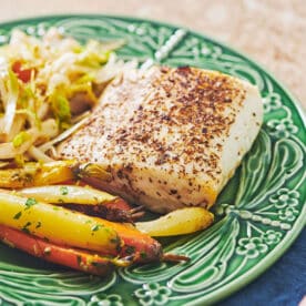 Roasted Cajun Cod on plate with carrots and salad.