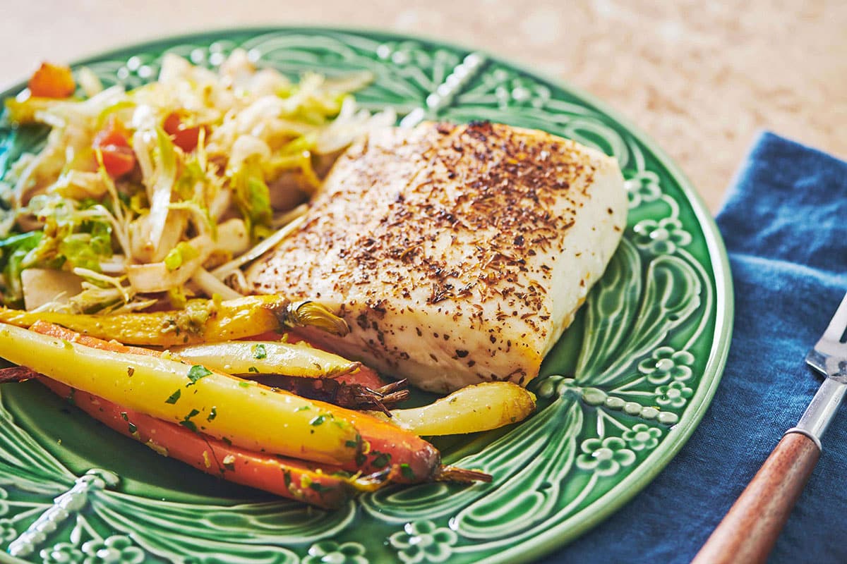 Roasted Cajun Cod on plate with carrots and salad.