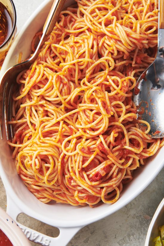 Spaghetti with Tomato Sauce in white platter with serving spoon and fork