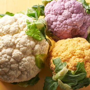 Colorful heads of fresh cauliflower on yellow surface.