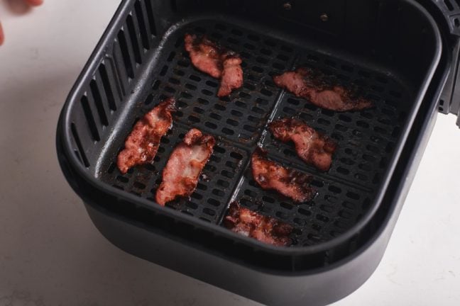 Cooked bacon in an Air Fryer basket.