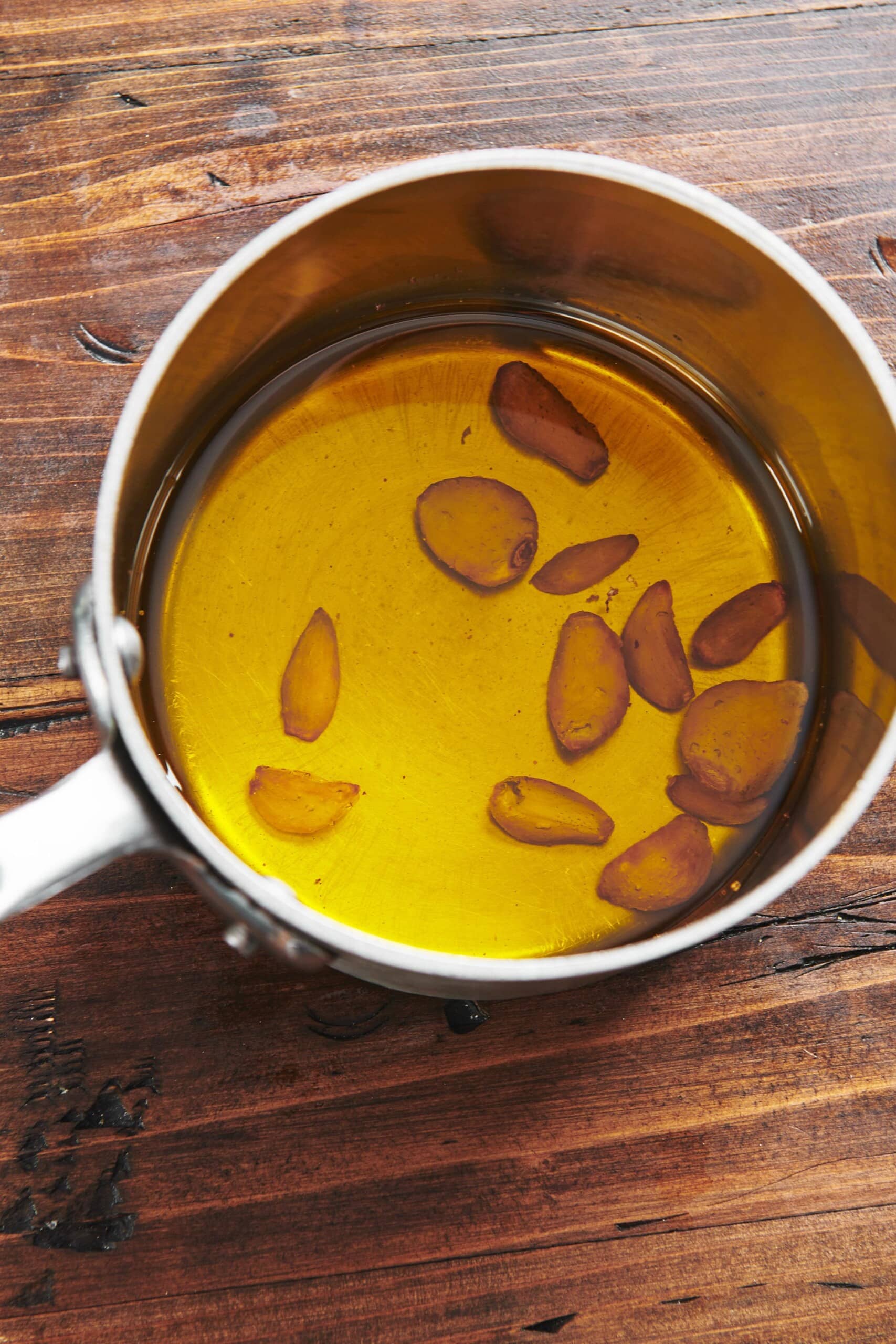 Garlic cloves in pan of oil.