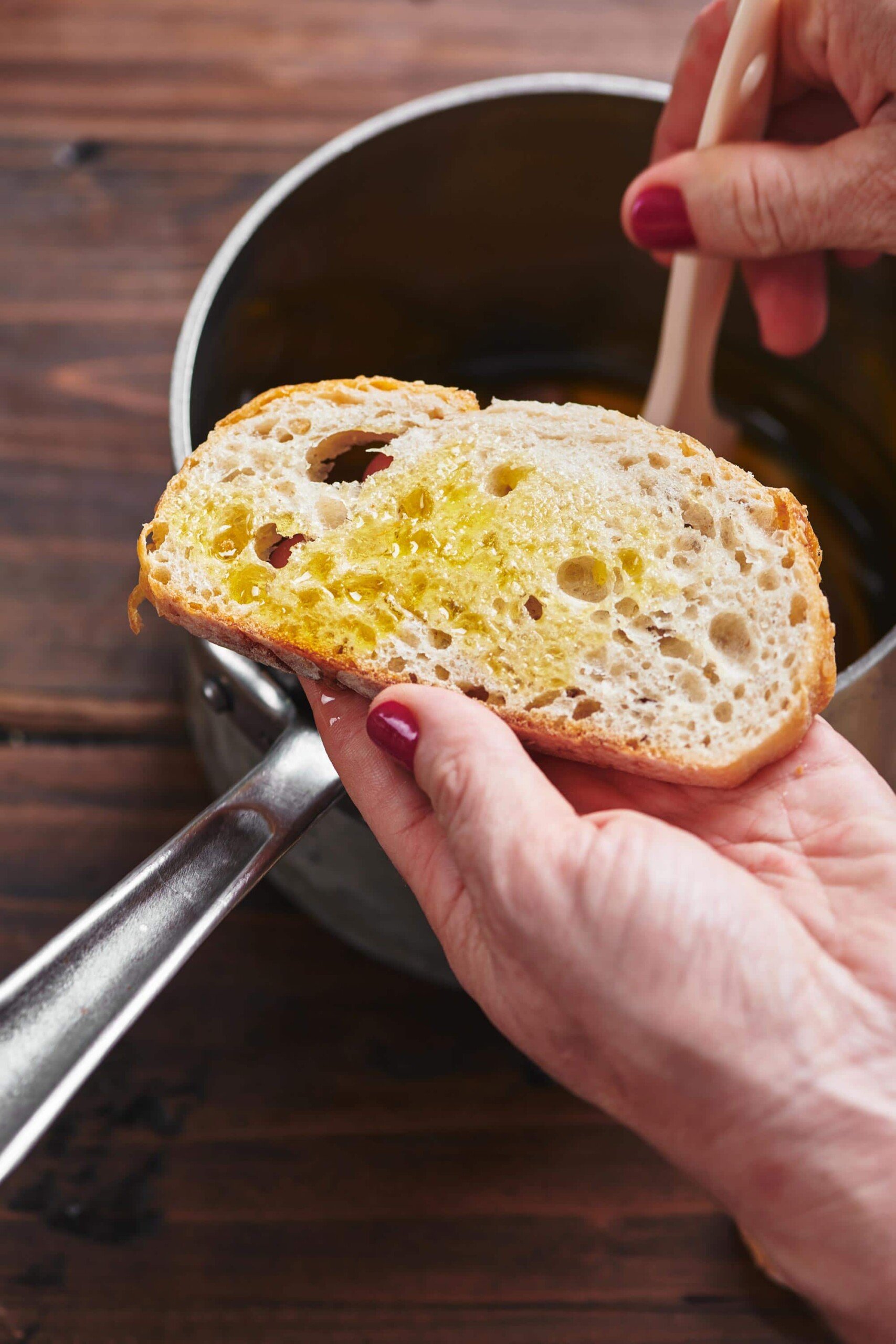 Woman using brush to coat bread slice with garlic oil.