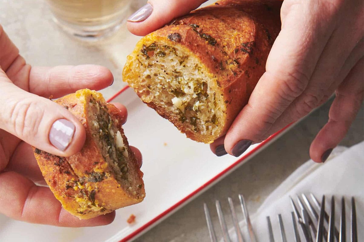 Woman pulling apart slices of Ranch Garlic Bread.