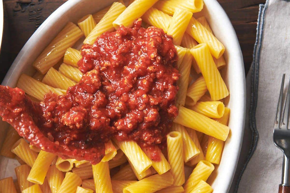Spoon adding Turkey Meat Sauce to pasta.