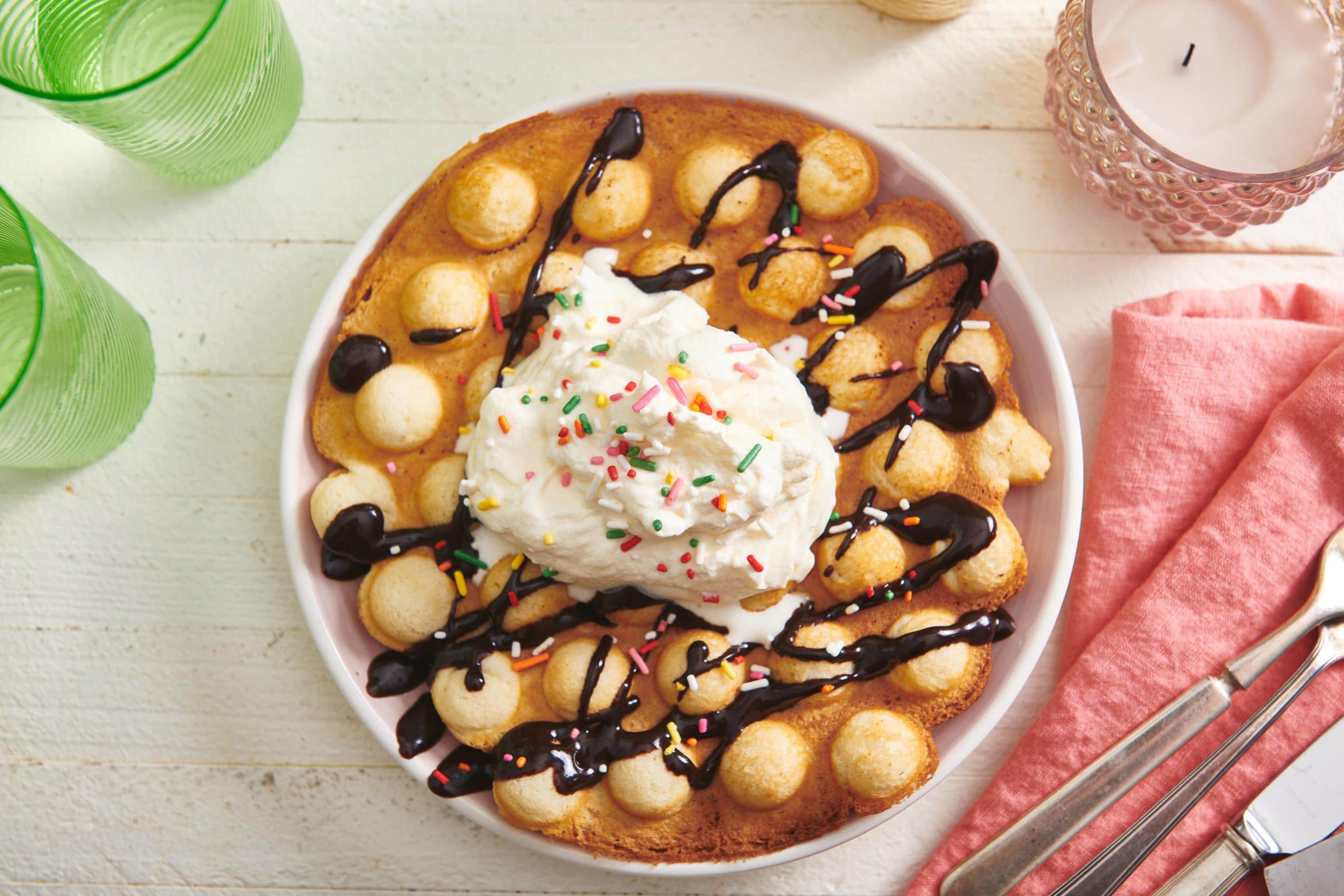 Bubble Waffle on a plate topped with ice cream, chocolate sauce, and sprinkles.