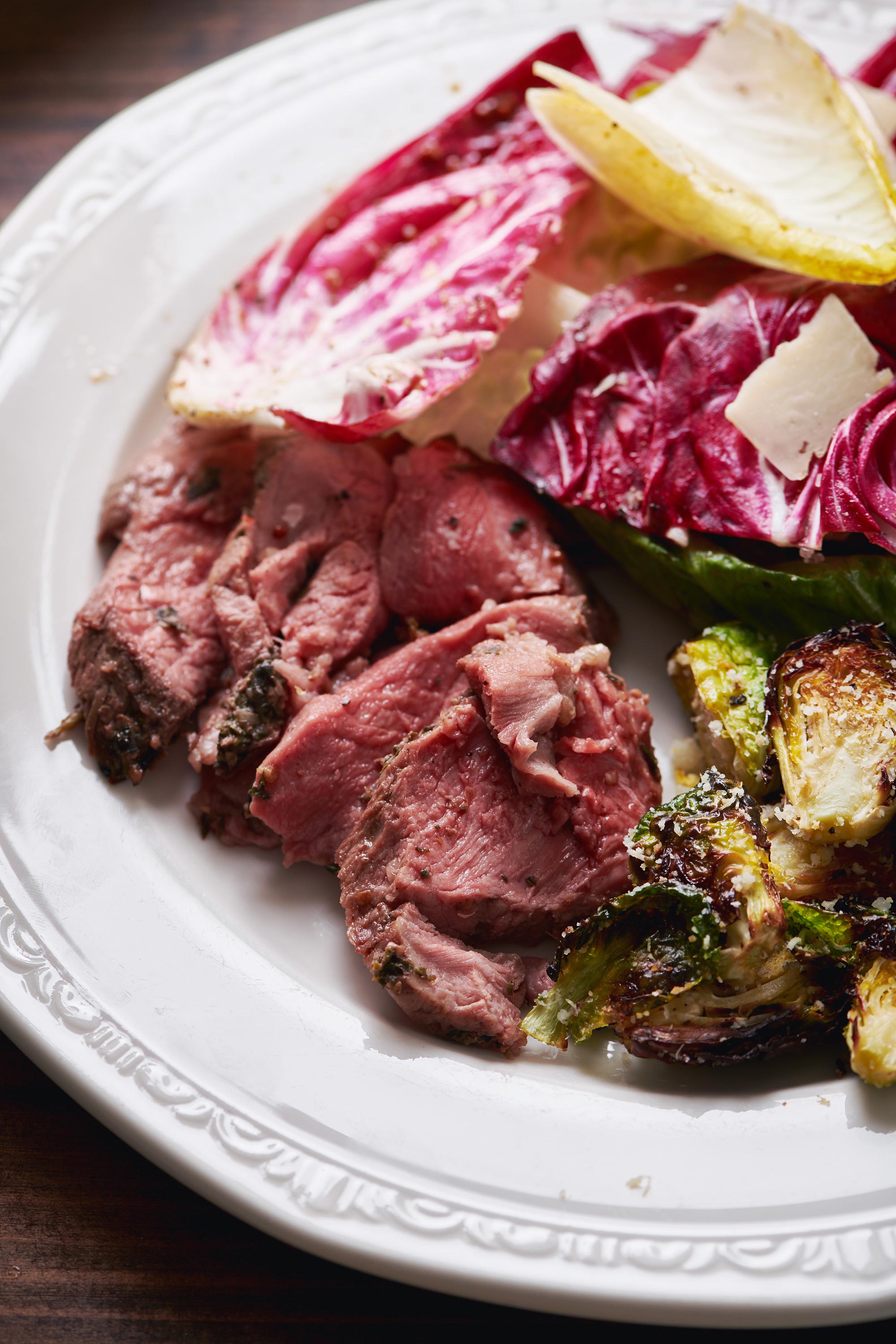 Greek-Style Butterflied Leg of Lamb with Feta Sauce on plate with Brussels sprouts.