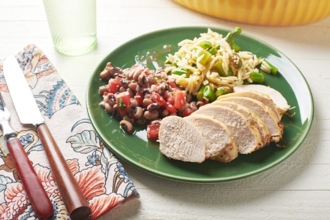Slices of Lemon Garlic Chicken Breasts on a plate with beans and rice.