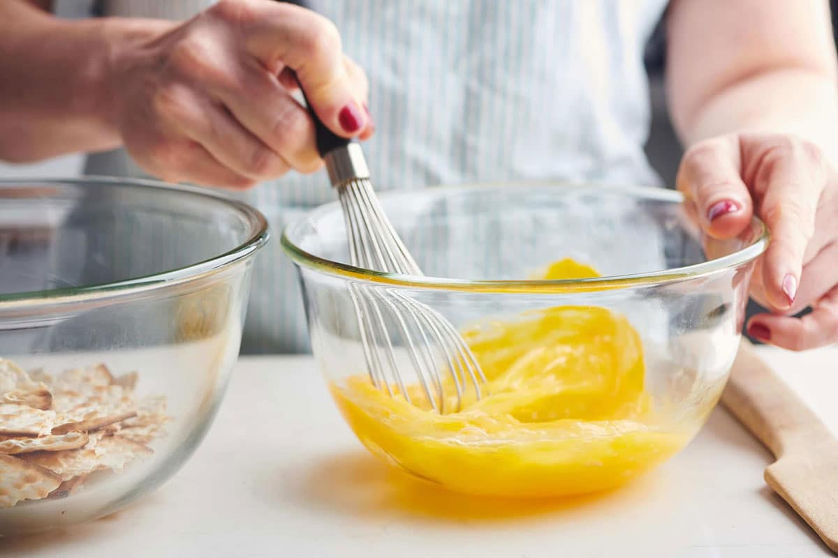 Woman beating eggs in glass bowl.