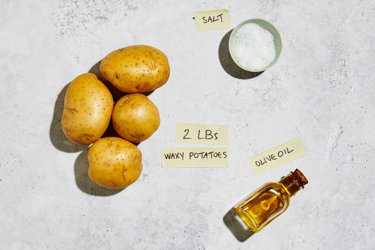 Potatoes, olive oil, and salt on marble table.
