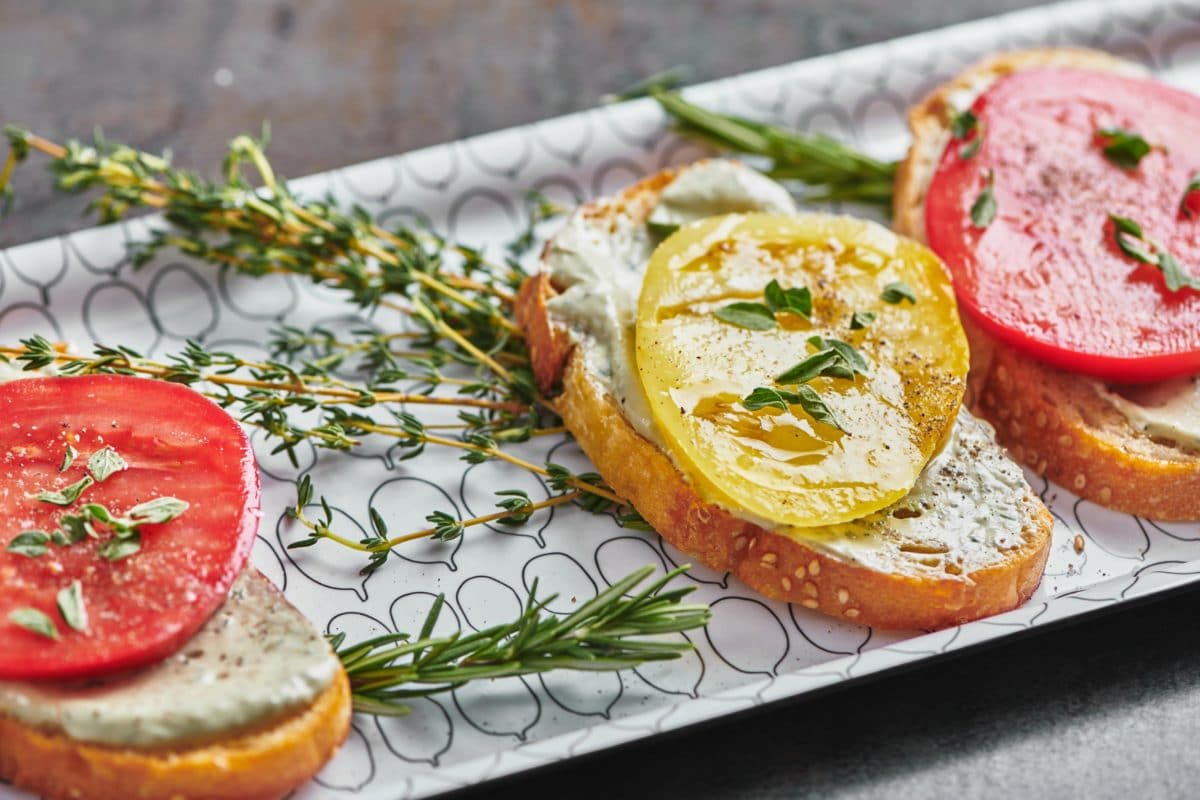 Bruschetta with Herbed Whipped Ricotta and red and yellow Heirloom Tomatoes on a plate.