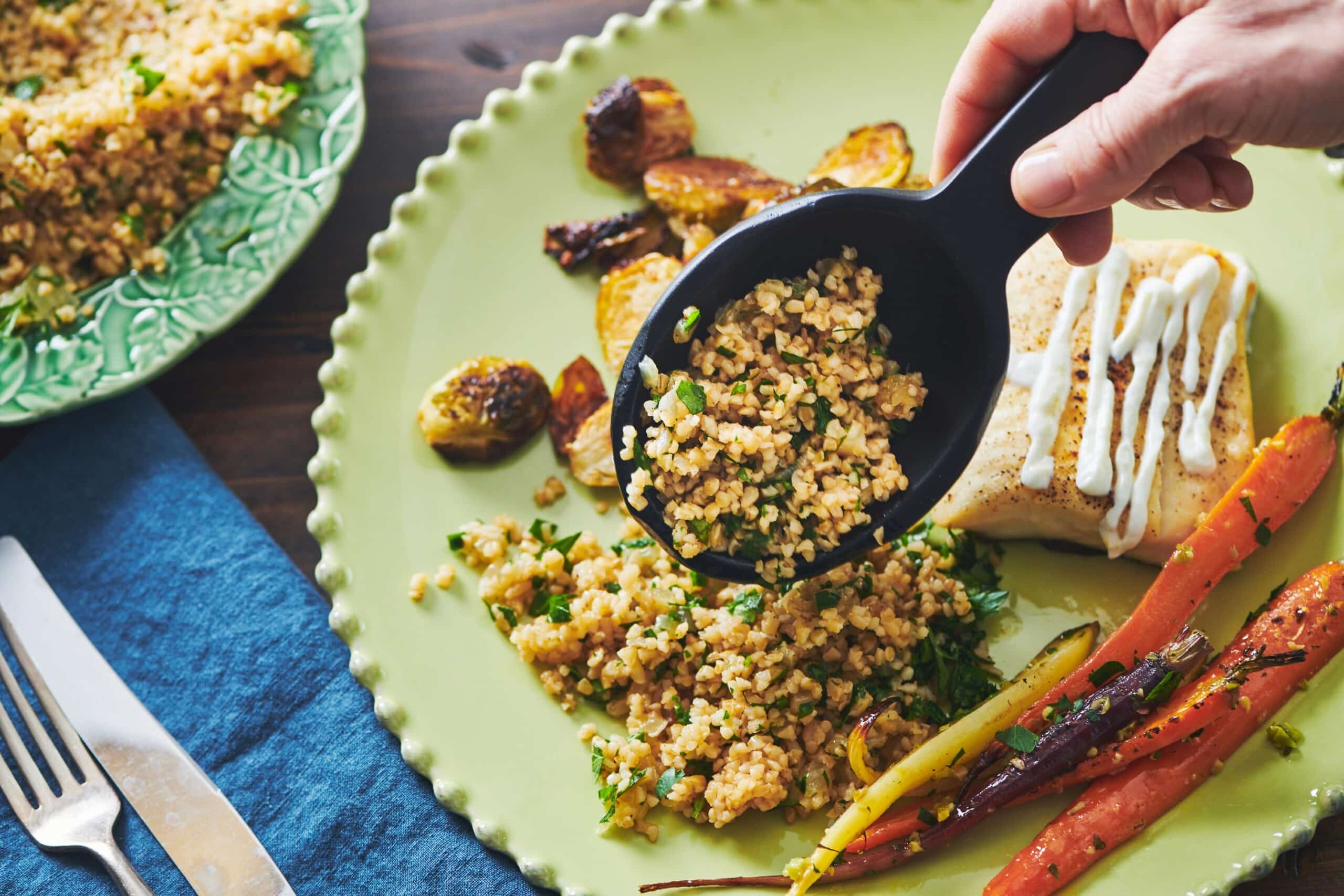 Pouring Bulgur Wheat with Caramelized Onions and Parsley onto green plate.