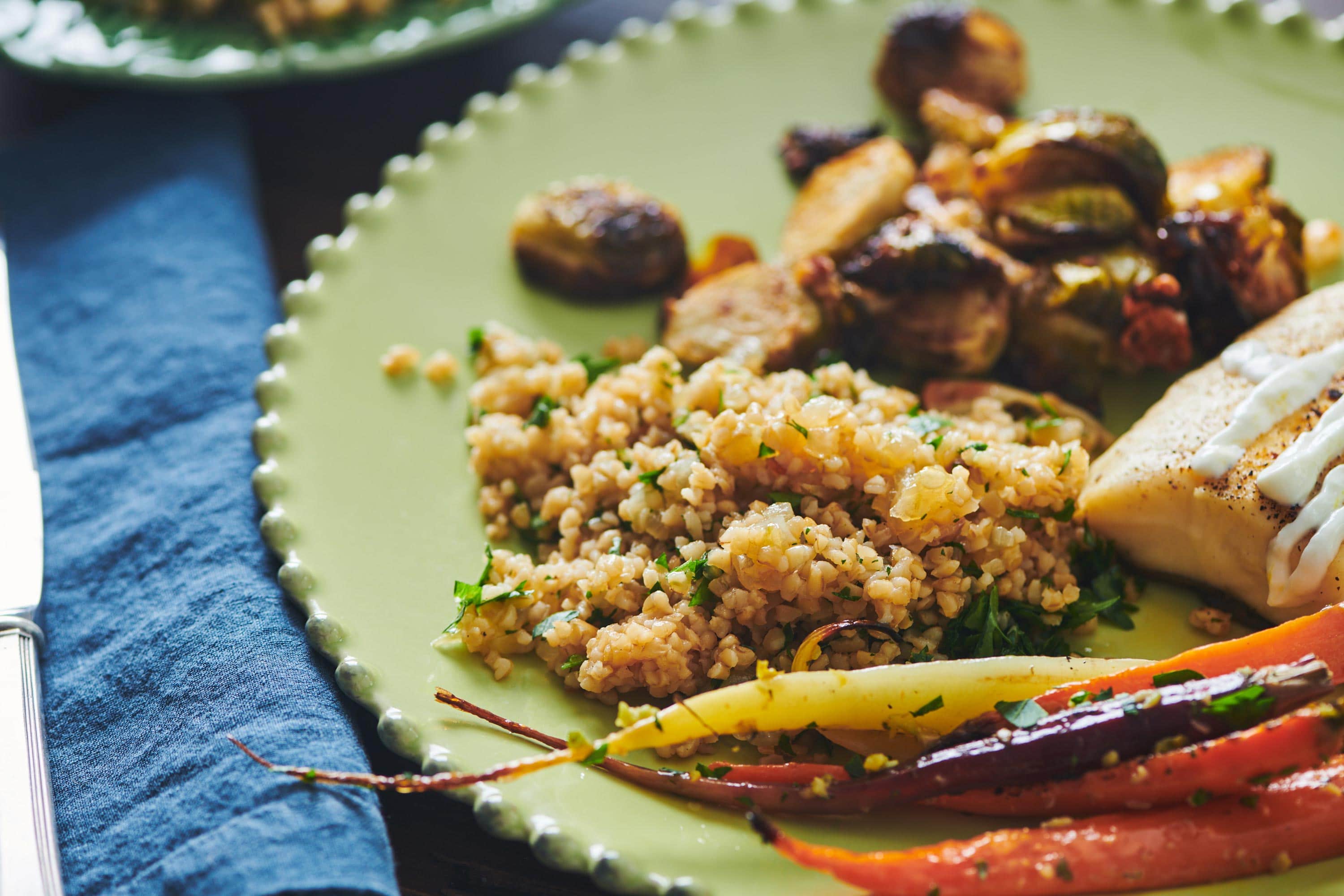 Bulgur Wheat with Caramelized Onions and Parsley, rainbow carrots, and brussels sprouts on a plate.