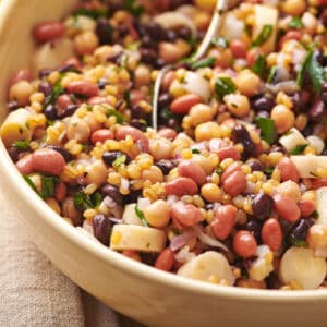 Bean salad in brown serving bowl on table.