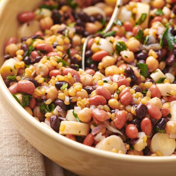 Bean salad in brown serving bowl on table.