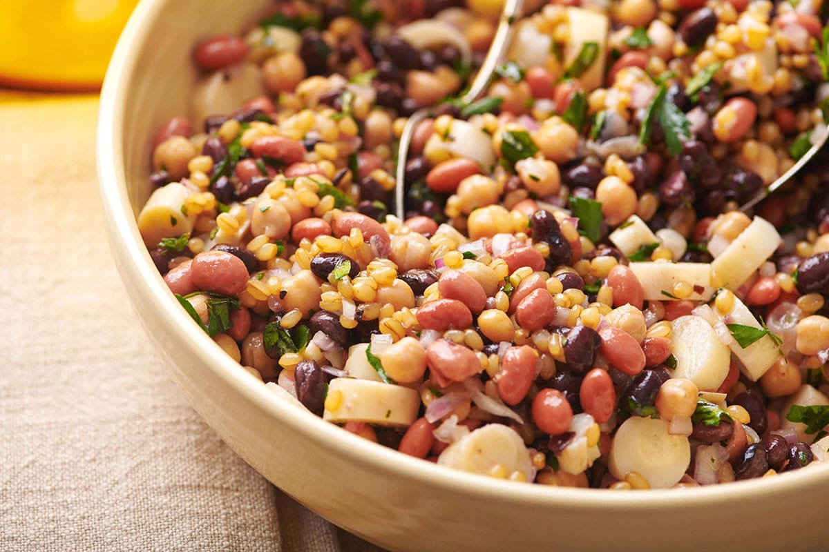 Bean salad in brown serving bowl on table.