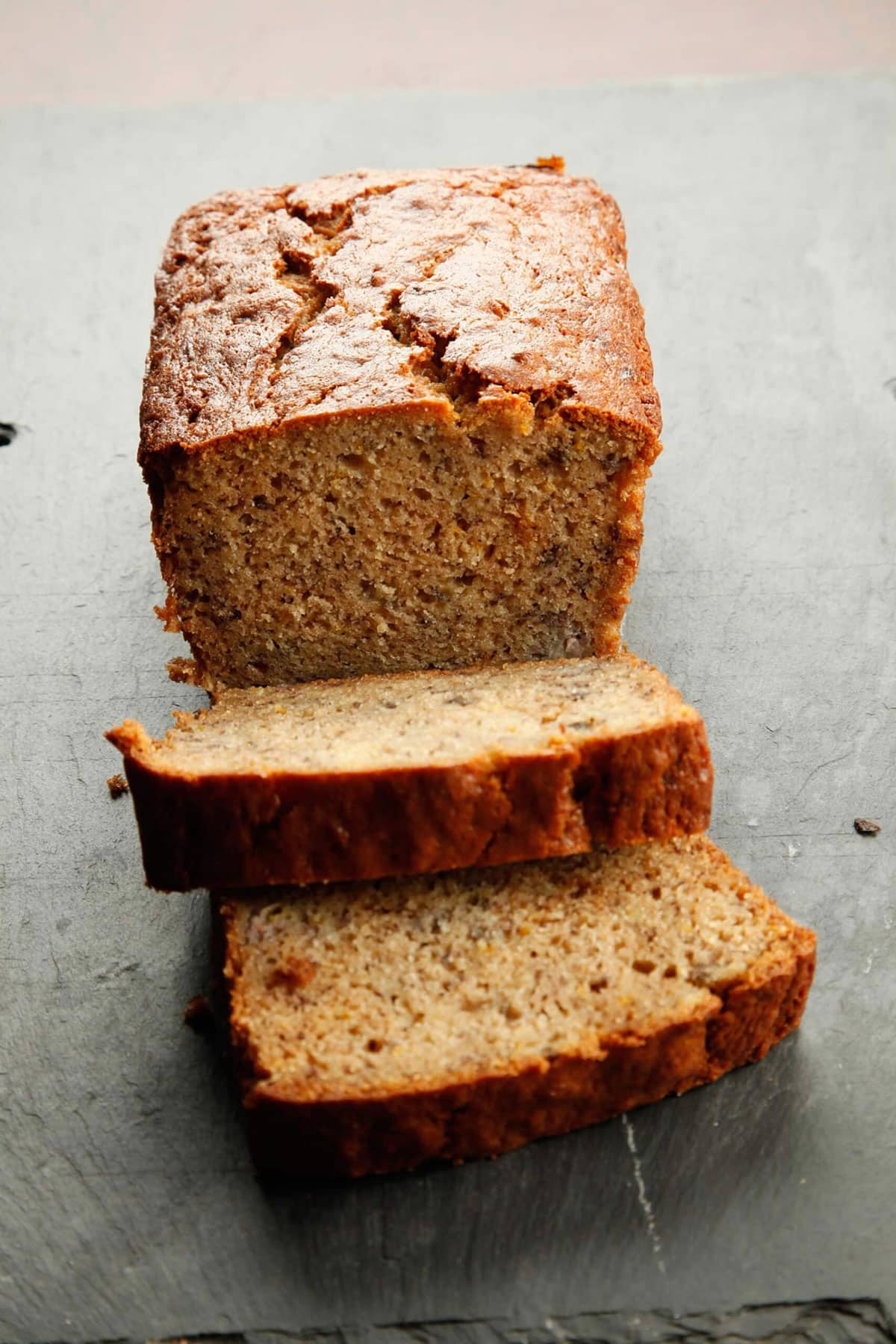 Banana bread partially sliced on counter.
