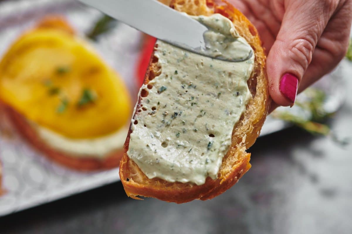 Knife spreading Herbed Whipped Ricotta onto bread.