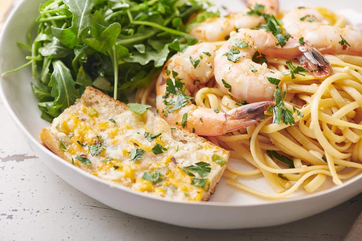 Cheesy Garlic Bread on a plate with shrimp and greens.