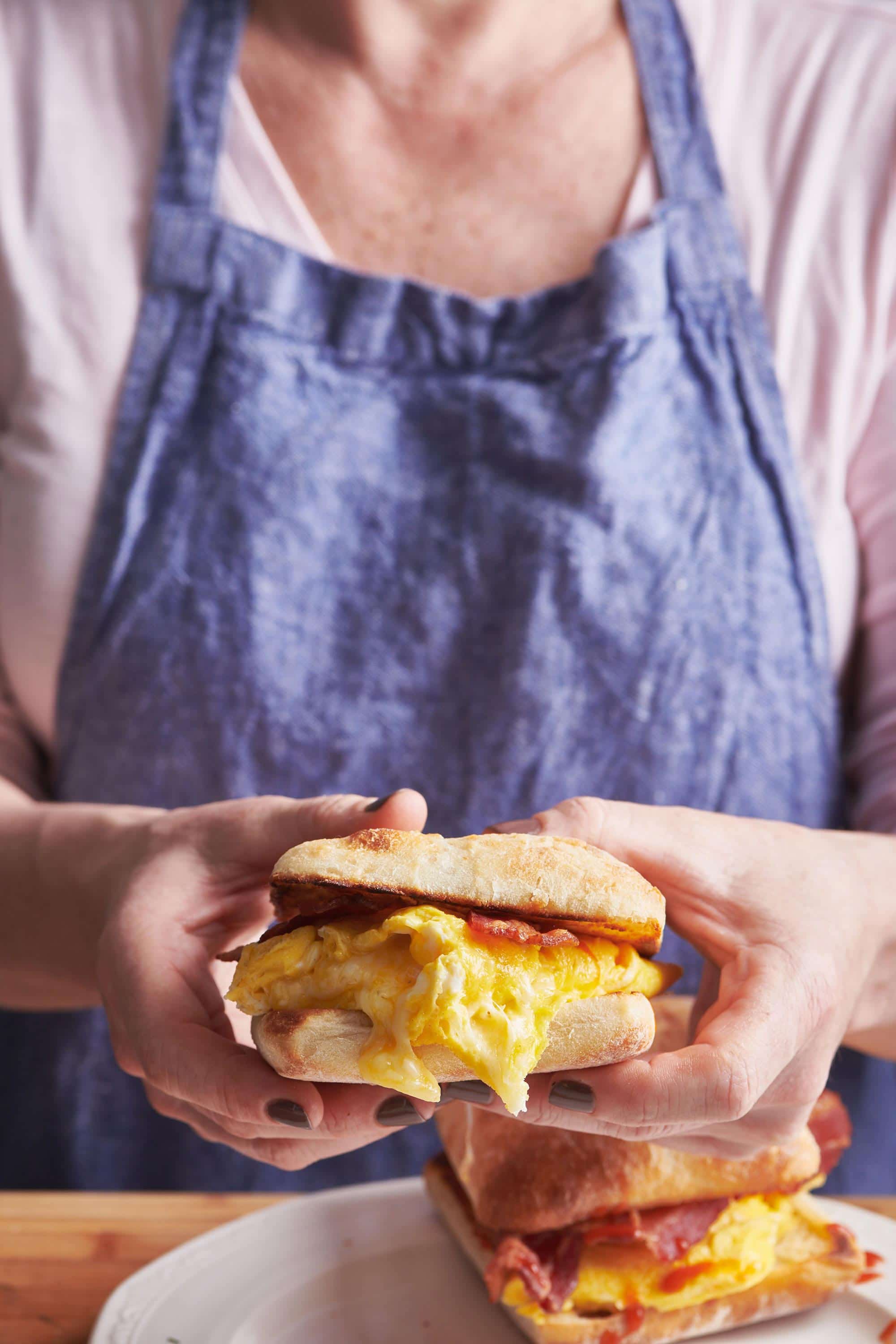 Woman holding a Classic Bacon, Egg and Cheese Sandwich.