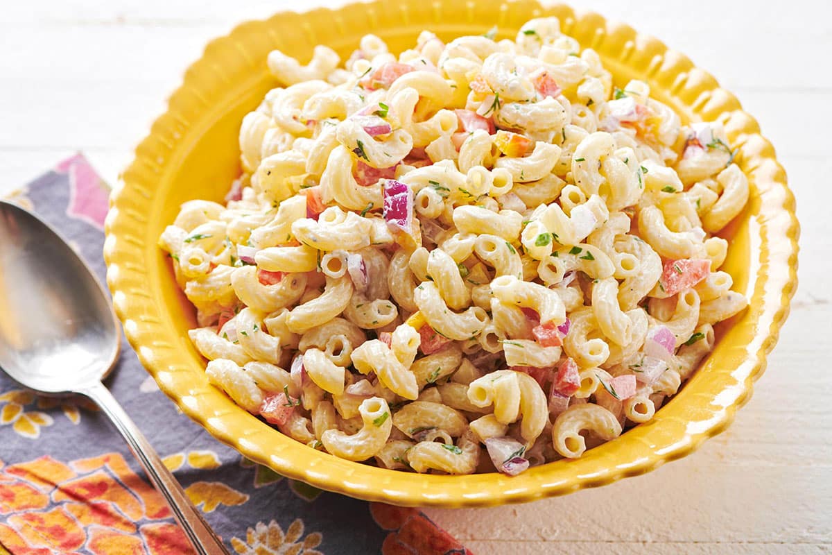 Old-fashioned macaroni salad in yellow bowl on table.
