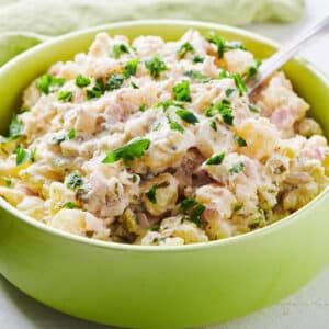 Spoon in a green bowl filled with potato salad.