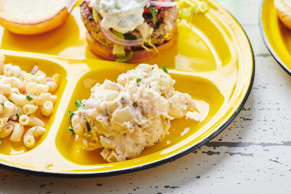 Potato Salad on a yellow plate with burger and macaroni salad.