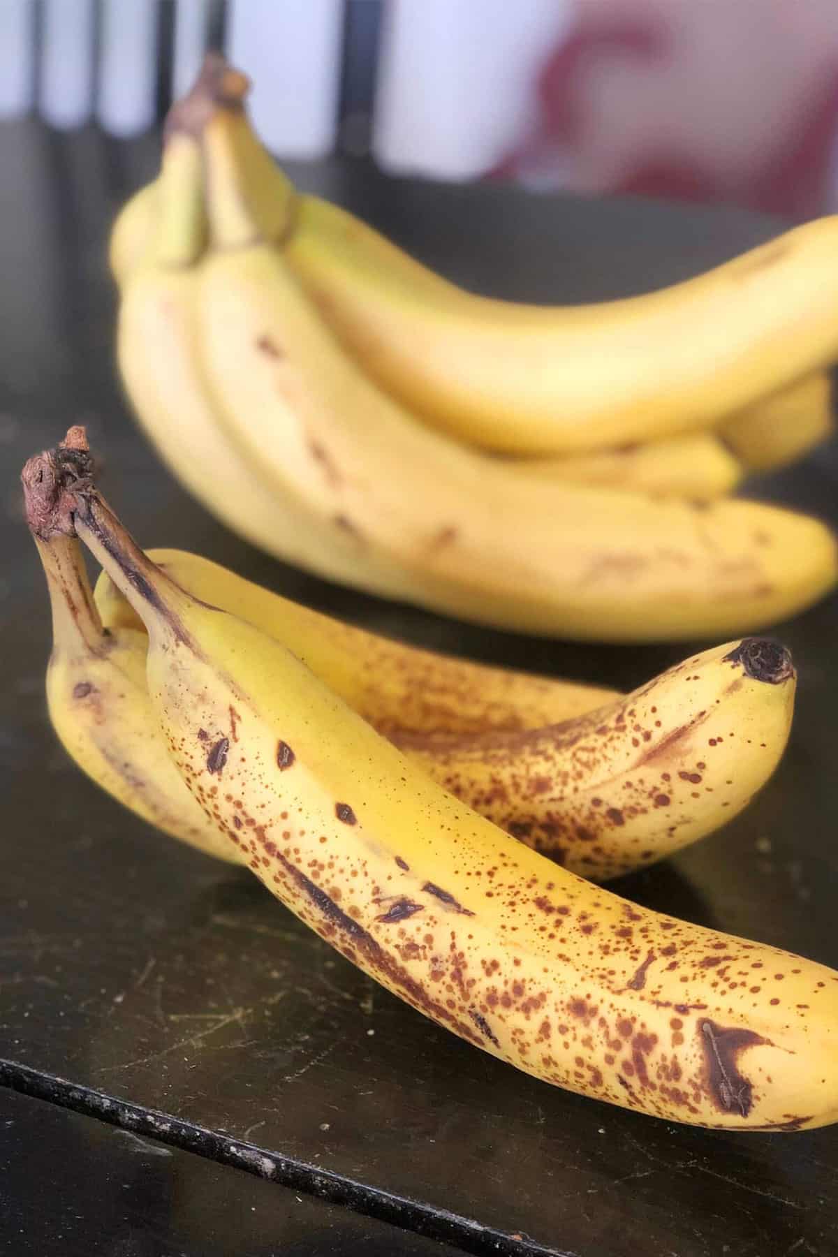 Two bunches of ripe bananas on kitchen counter.