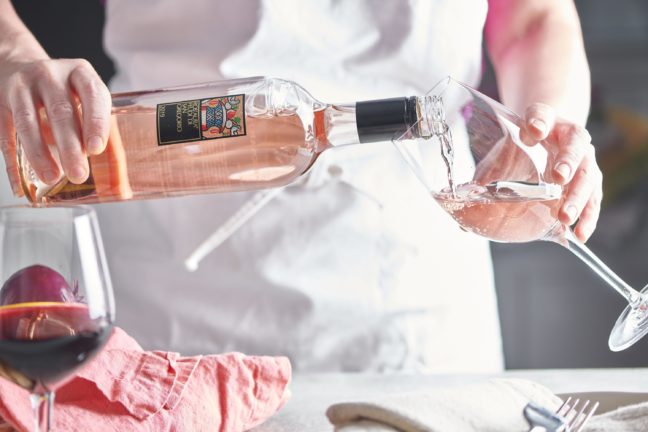 Woman pouring rose wine into a wine glass.