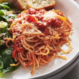 Spaghetti in tomato sauce on plate with green salad.
