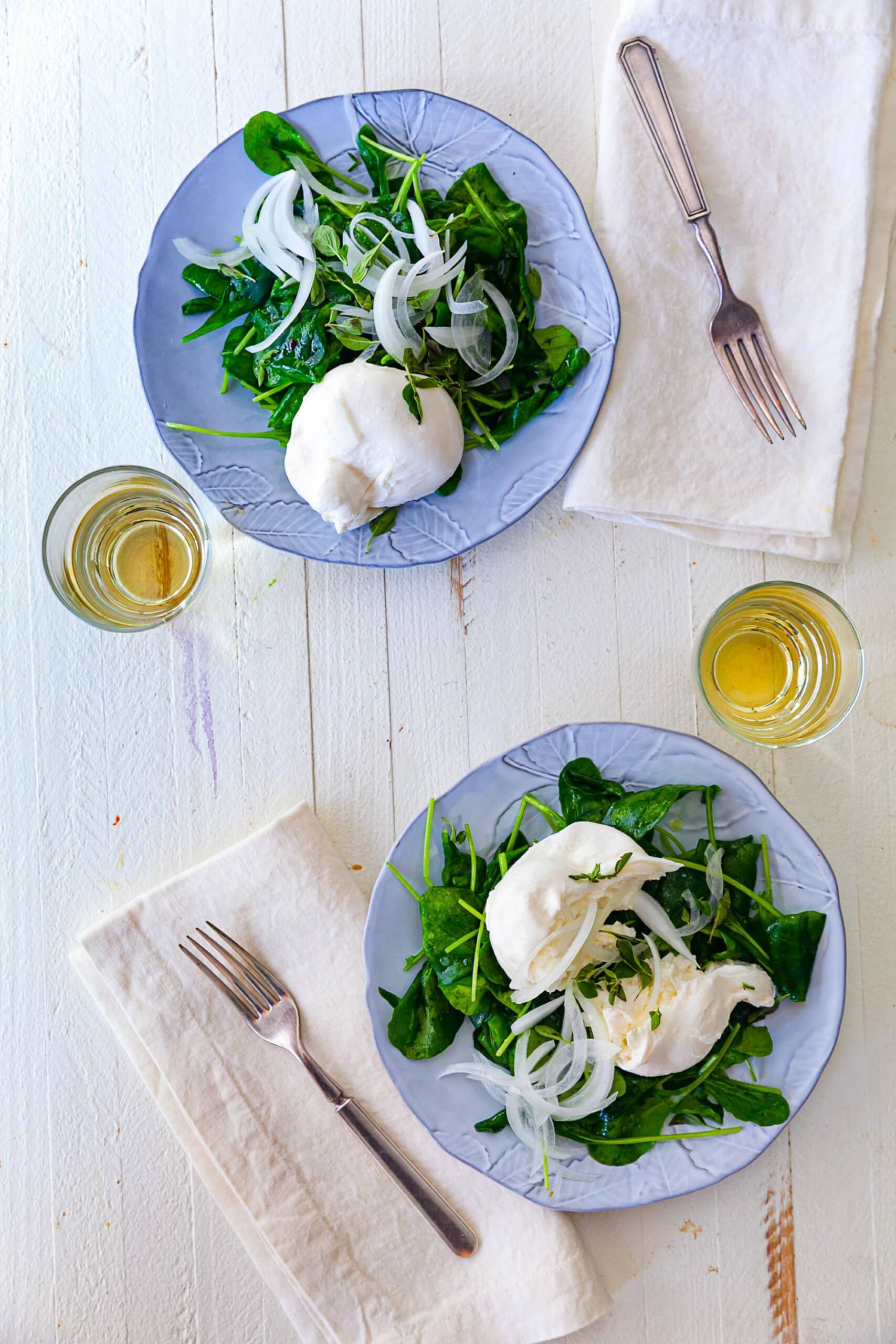 Spinach Salad with Burrata cheese on blue plates.