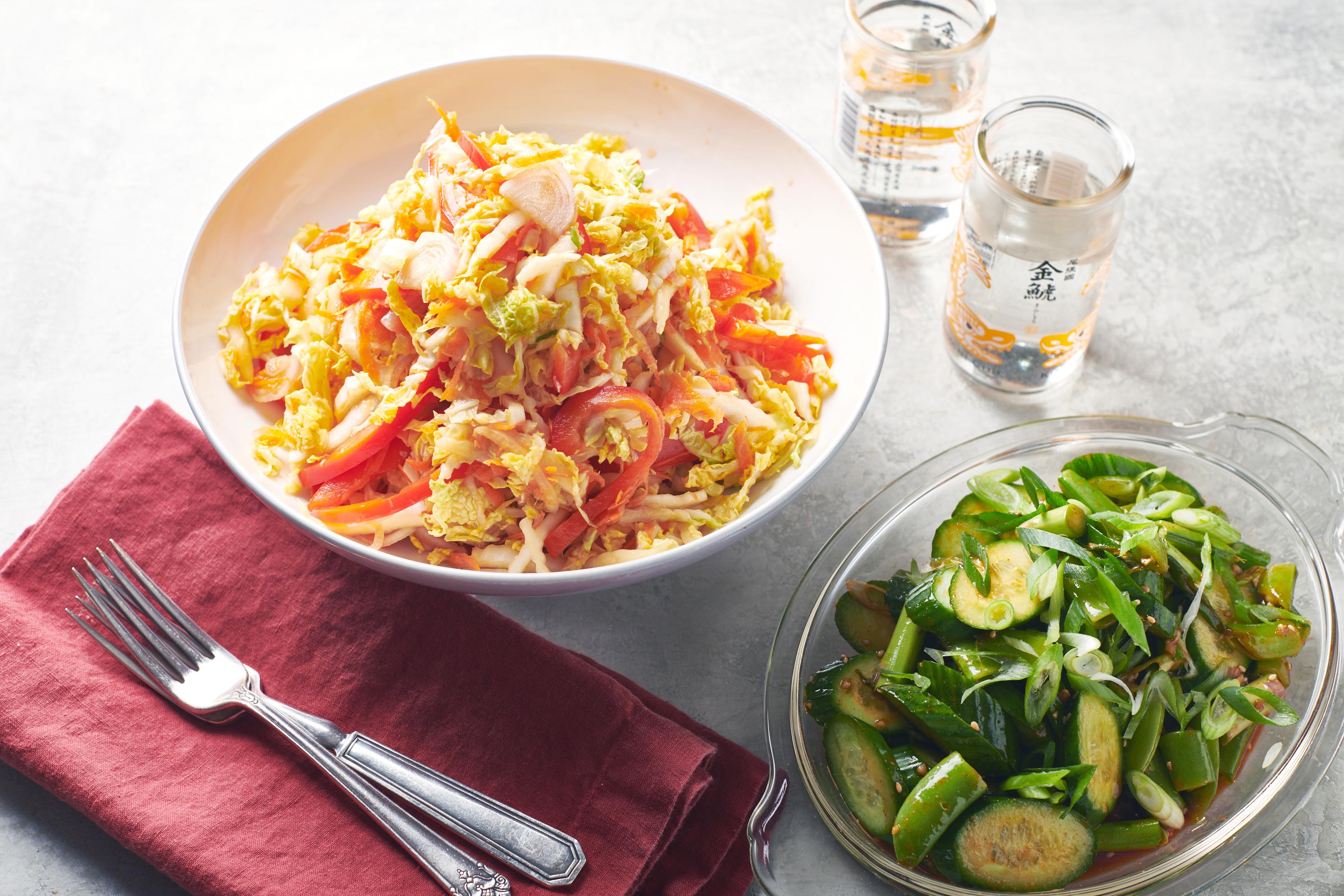 Vegan Asian Napa Cabbage Slaw on a table with greens, water glasses, and silverware.