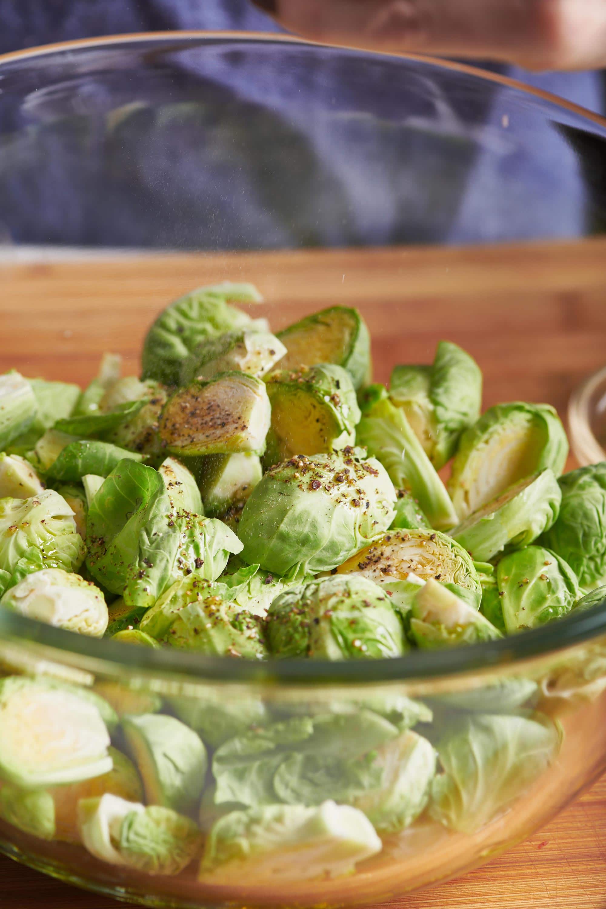 Seasoned, halved brussels sprouts in a glass bowl.