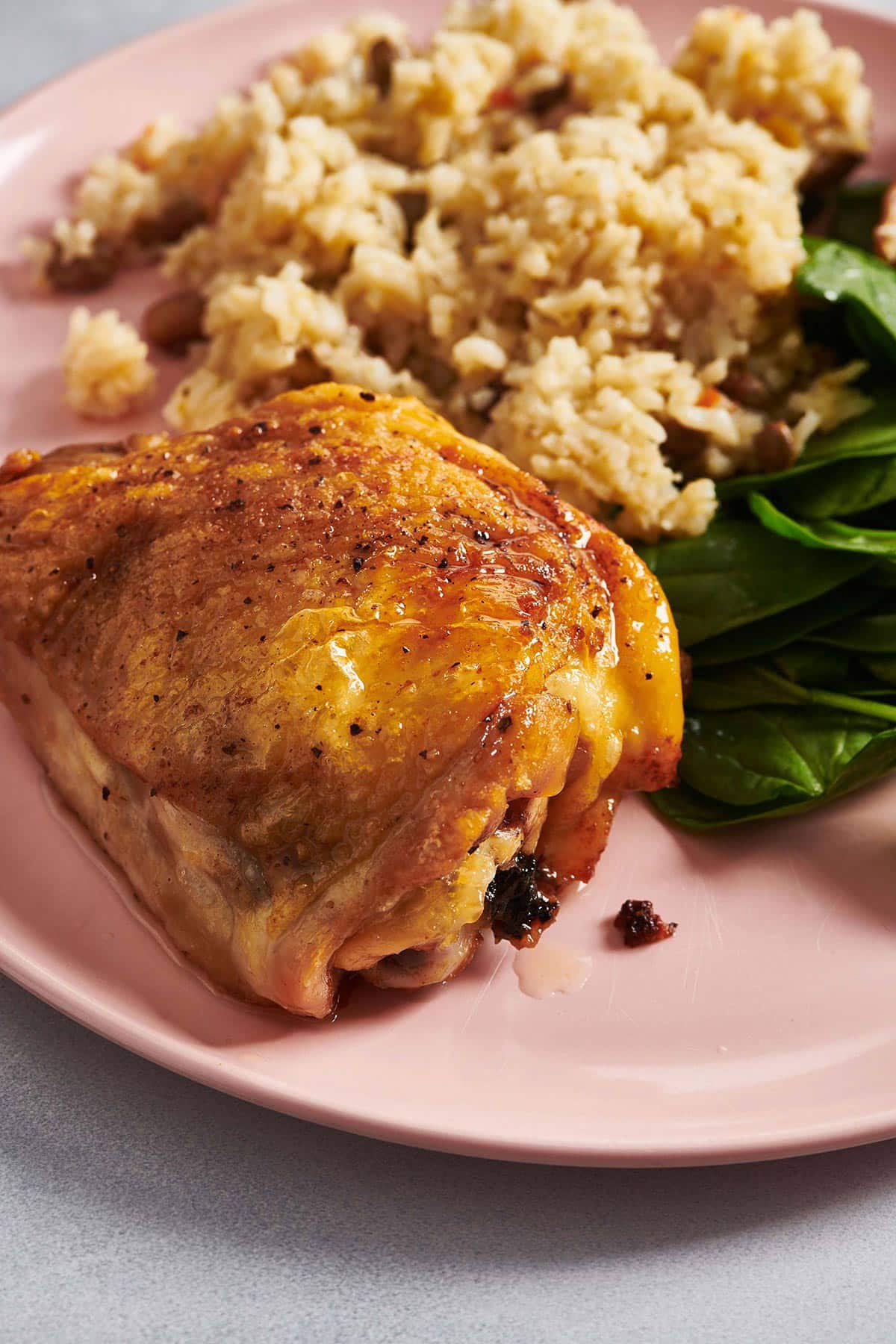 Garlic Butter Chicken Thigh on a plate with greens and grains.