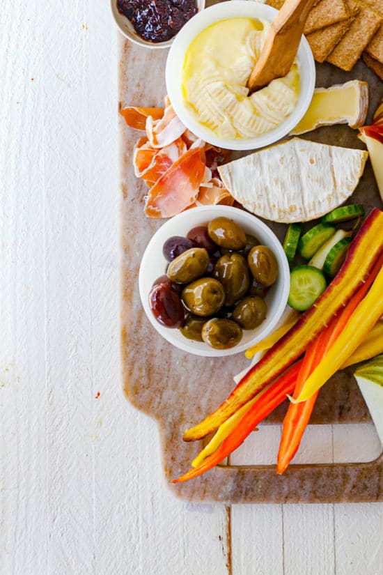 Olives, cheese, vegetables, and meat on a board.