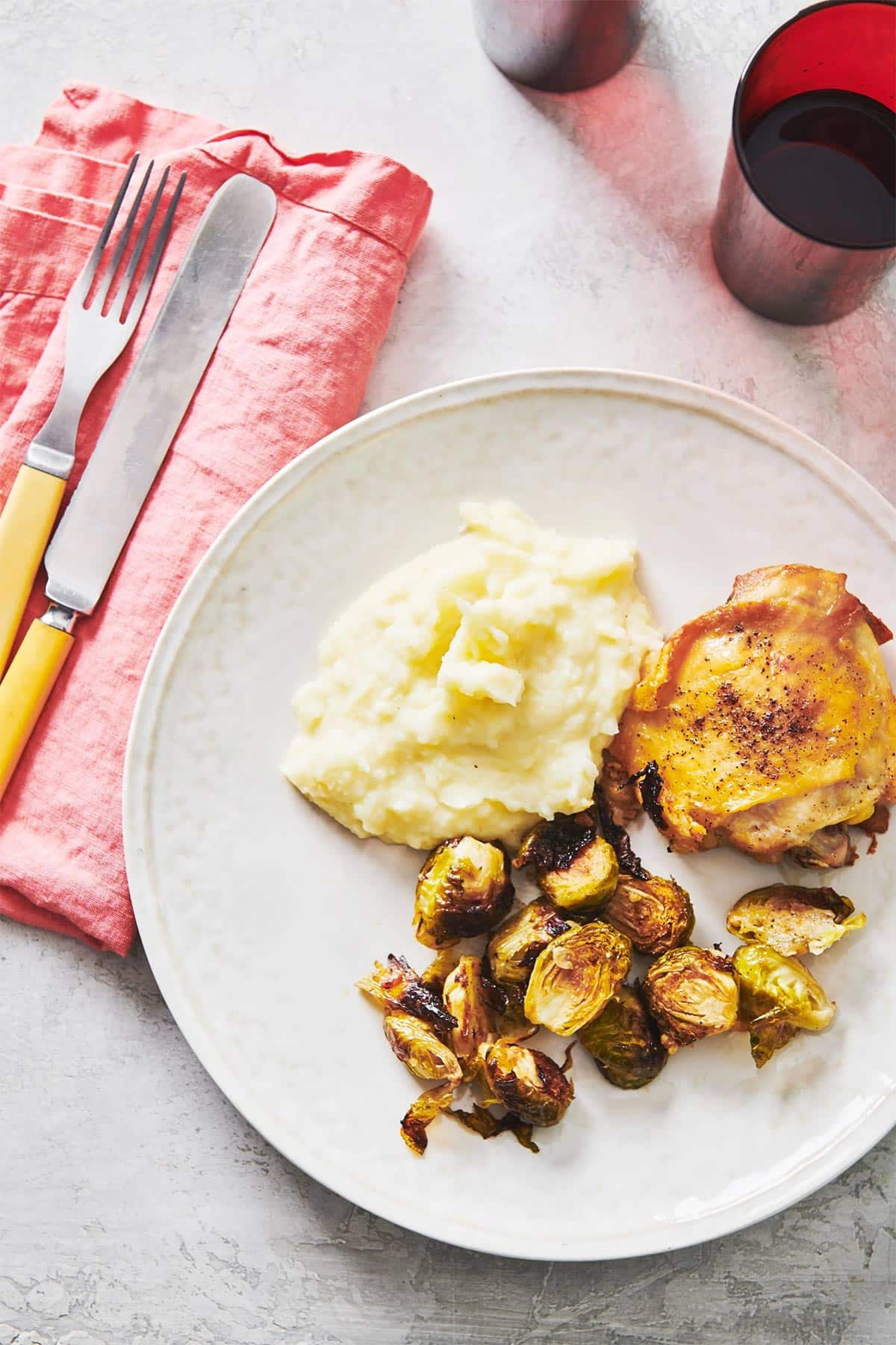 Roasted Chicken Thighs on plate with mashed potatoes and Brussels sprouts.