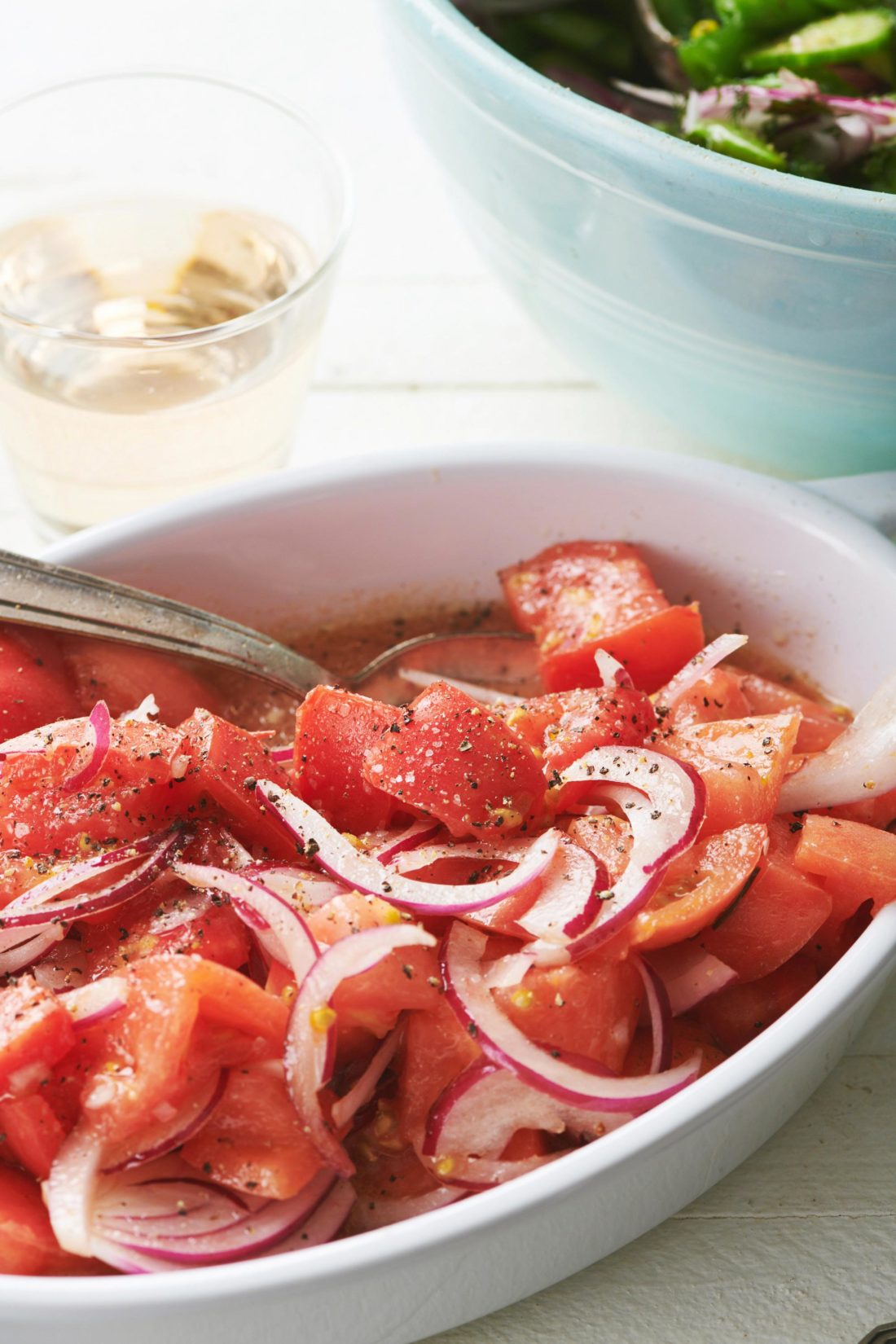 Steakhouse Tomato Salad in a white bowl with a spoon.