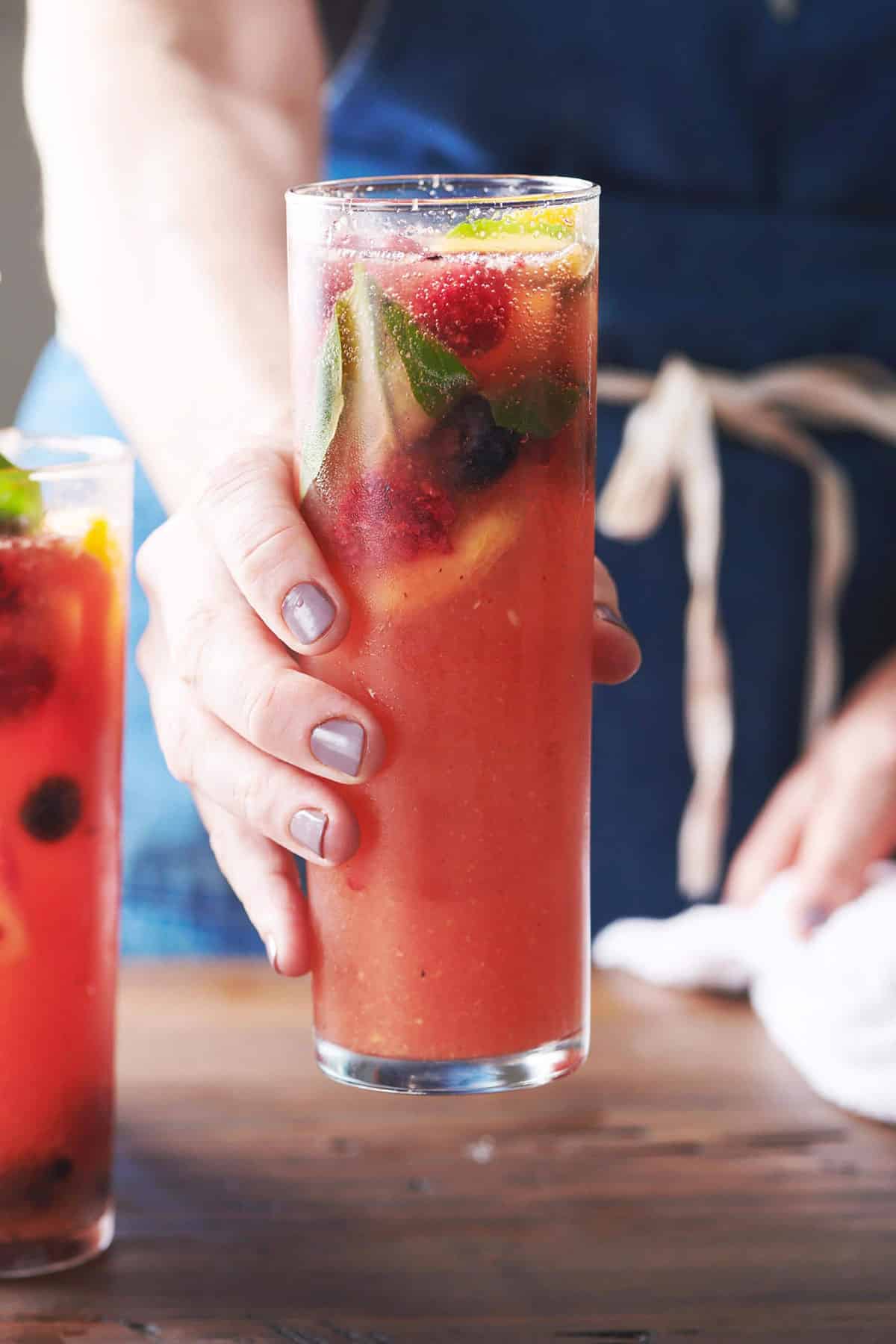 Woman holding a glass of Fruit and Berry Sangria.