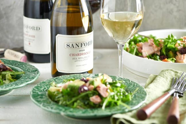 Bottle and glass of Sanford Chardonnay with a plate of salmon avocado salad.