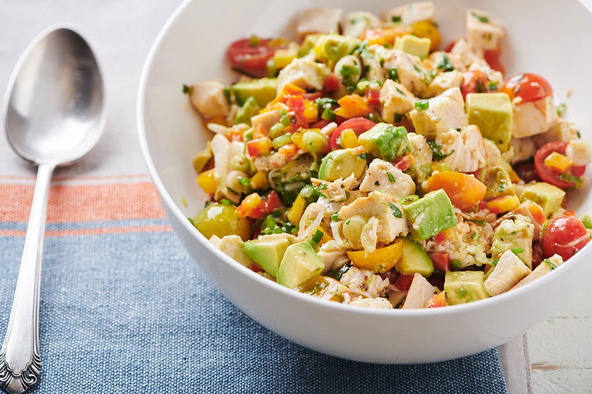 Chicken and Avocado Salad in white bowl next to spoon.