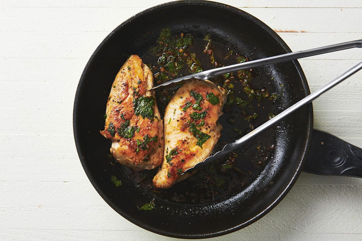 Cooking chicken breasts with cilantro-lime sauce in cast iron skillet.